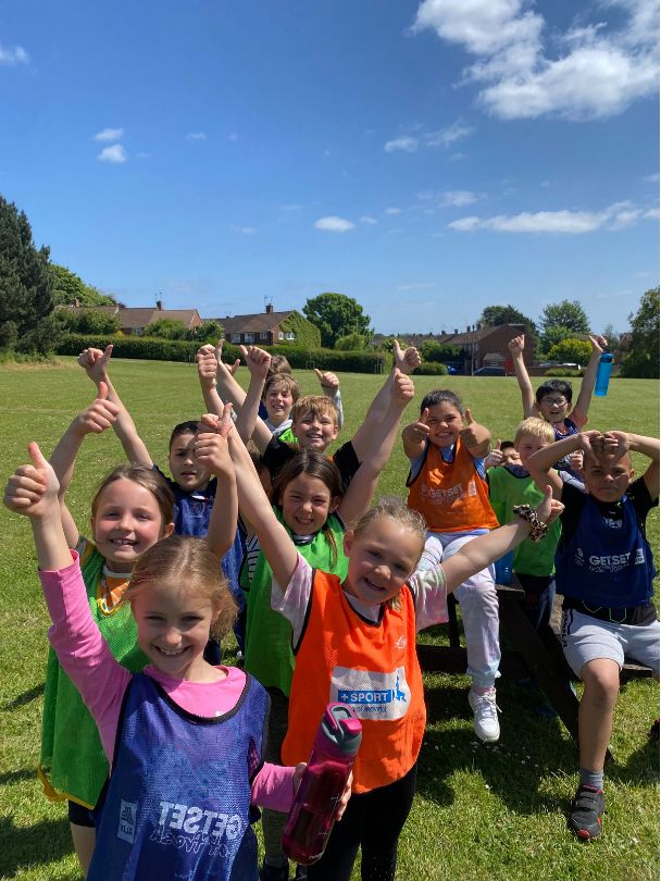 A group of children smiling and giving a thumbs up during a Challenge session